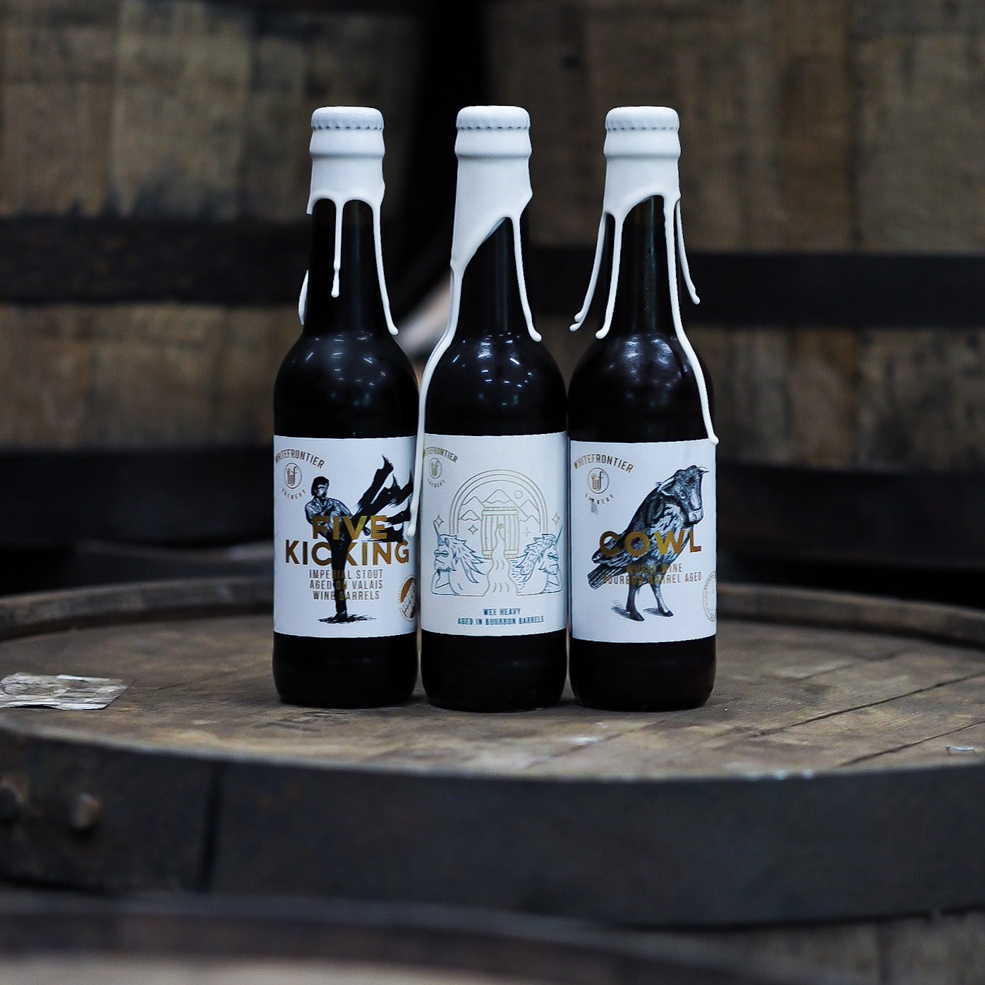 3 bières barrel aged avec de la cire posées sur un barrique