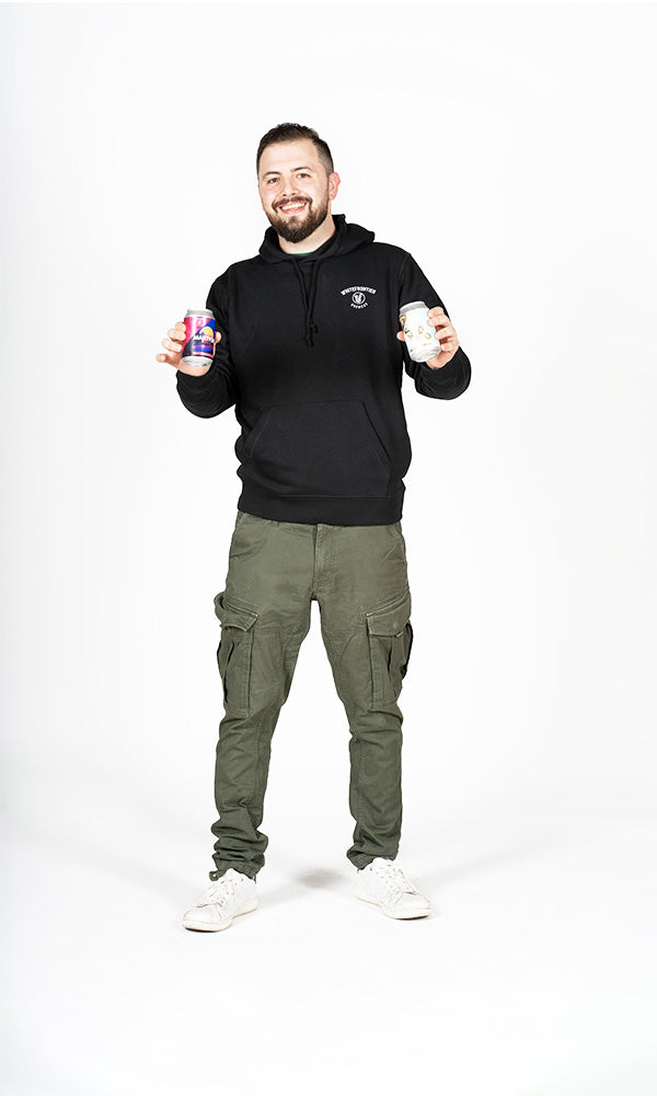 Homme en sweat noir et pantalon vert avec des canettes de bière