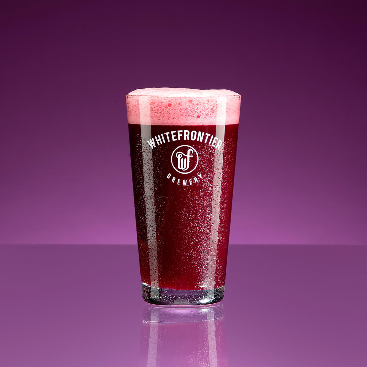un verre de bière pourpre sur fond violet