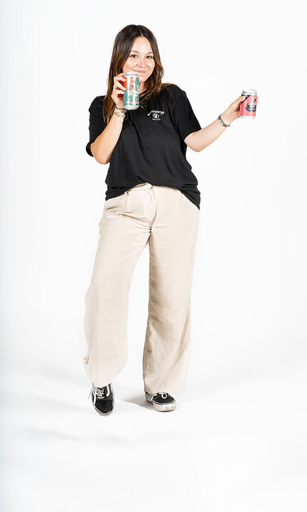 Femme en pantalon blanc et t-shirt noir avec canette de bière