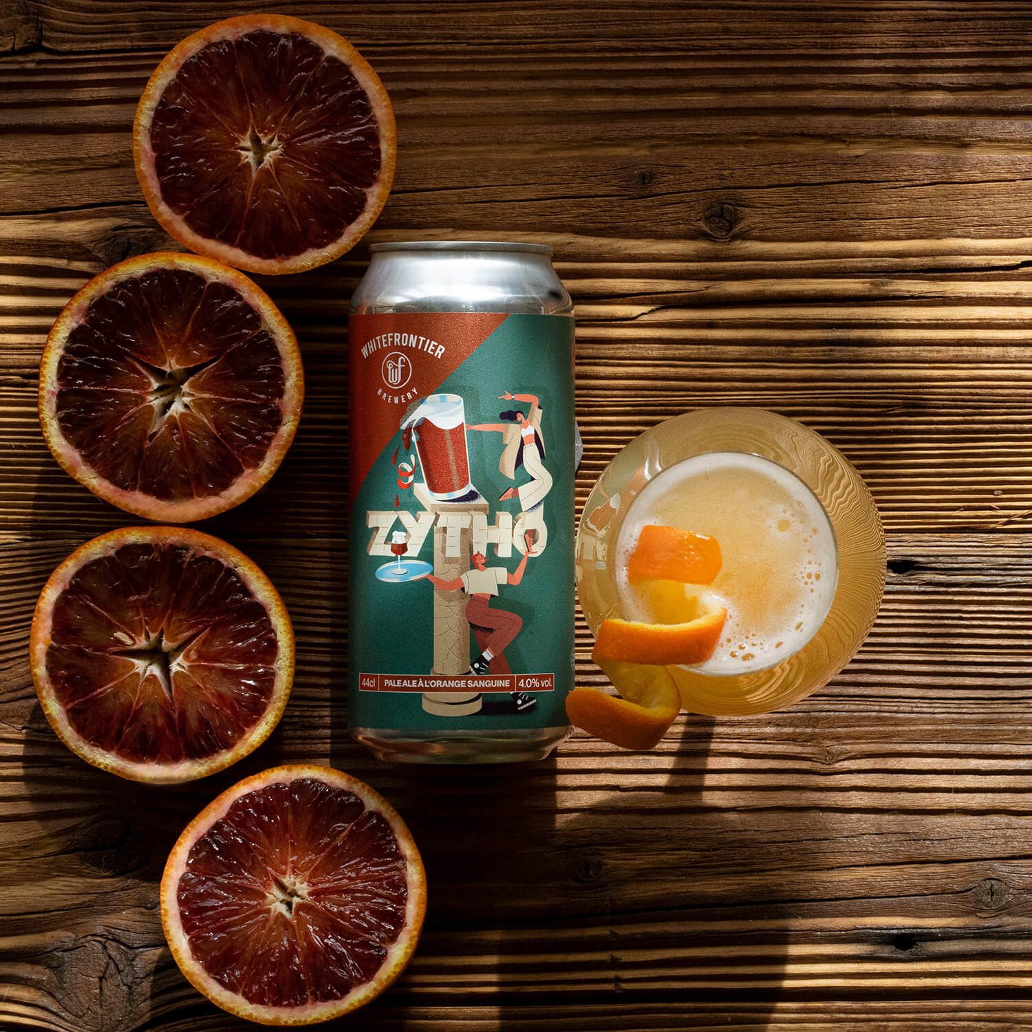 une biere canette avec un verre tek sur du bois avec un zeste d'orange et des oranges sanguines