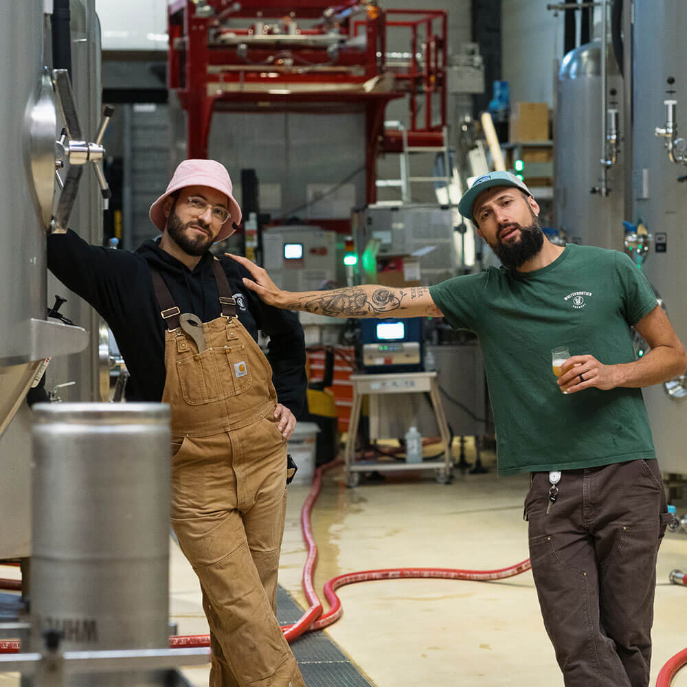 Blaise et Tom contre une cuve à la brasserie