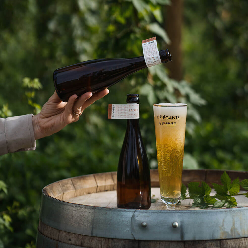 Bière élégante versée dans un beau verre posé sur un tonneau. La bière a une magnifique mousse