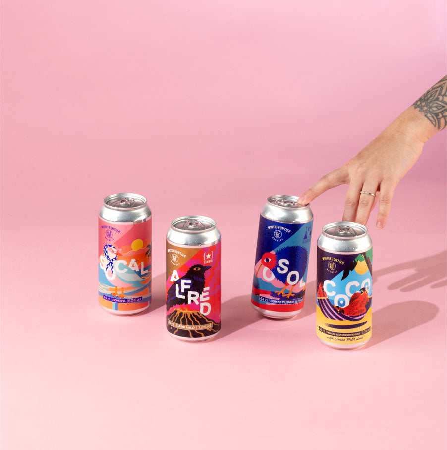 4 canettes sur fond rose avec des mains