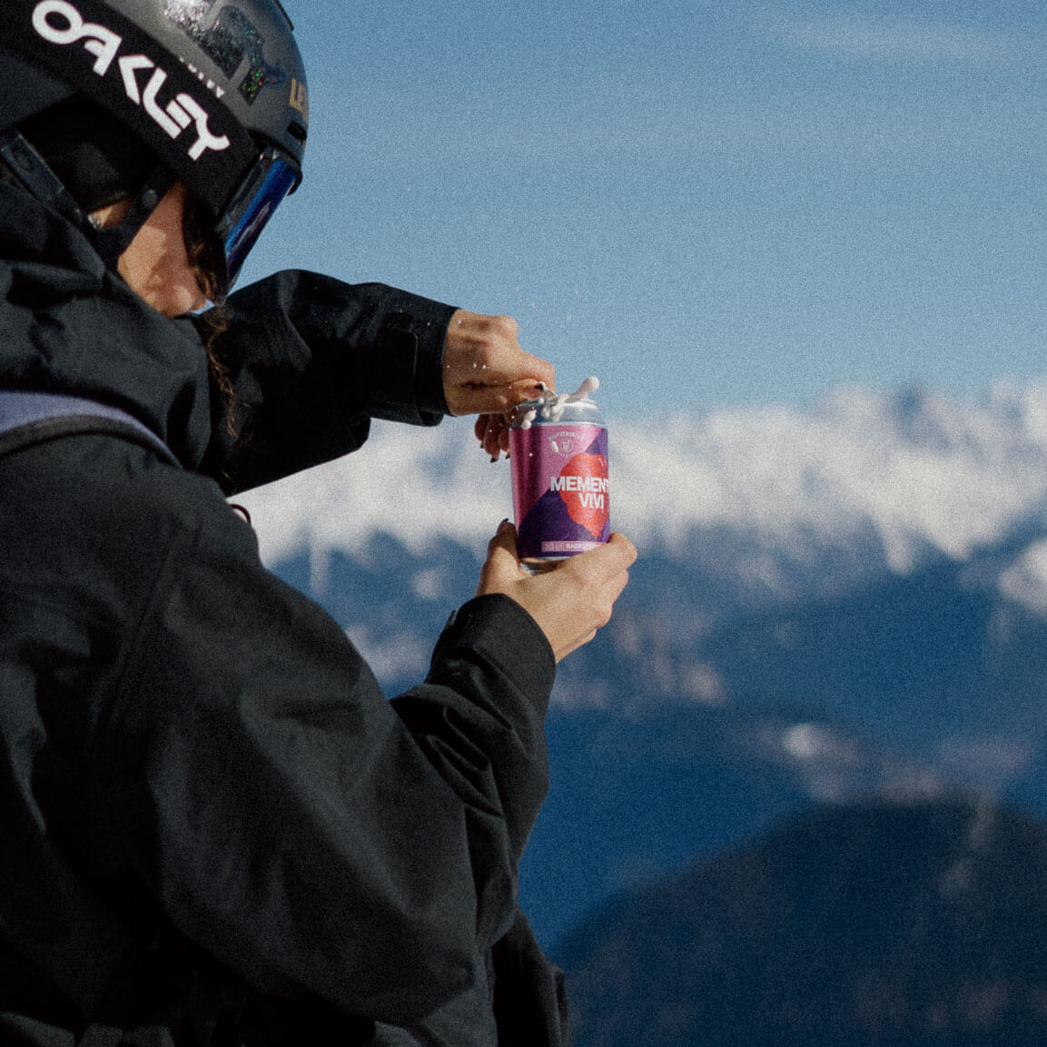 Une fille ouvre une canette davant un beau panorama et la bière mousse