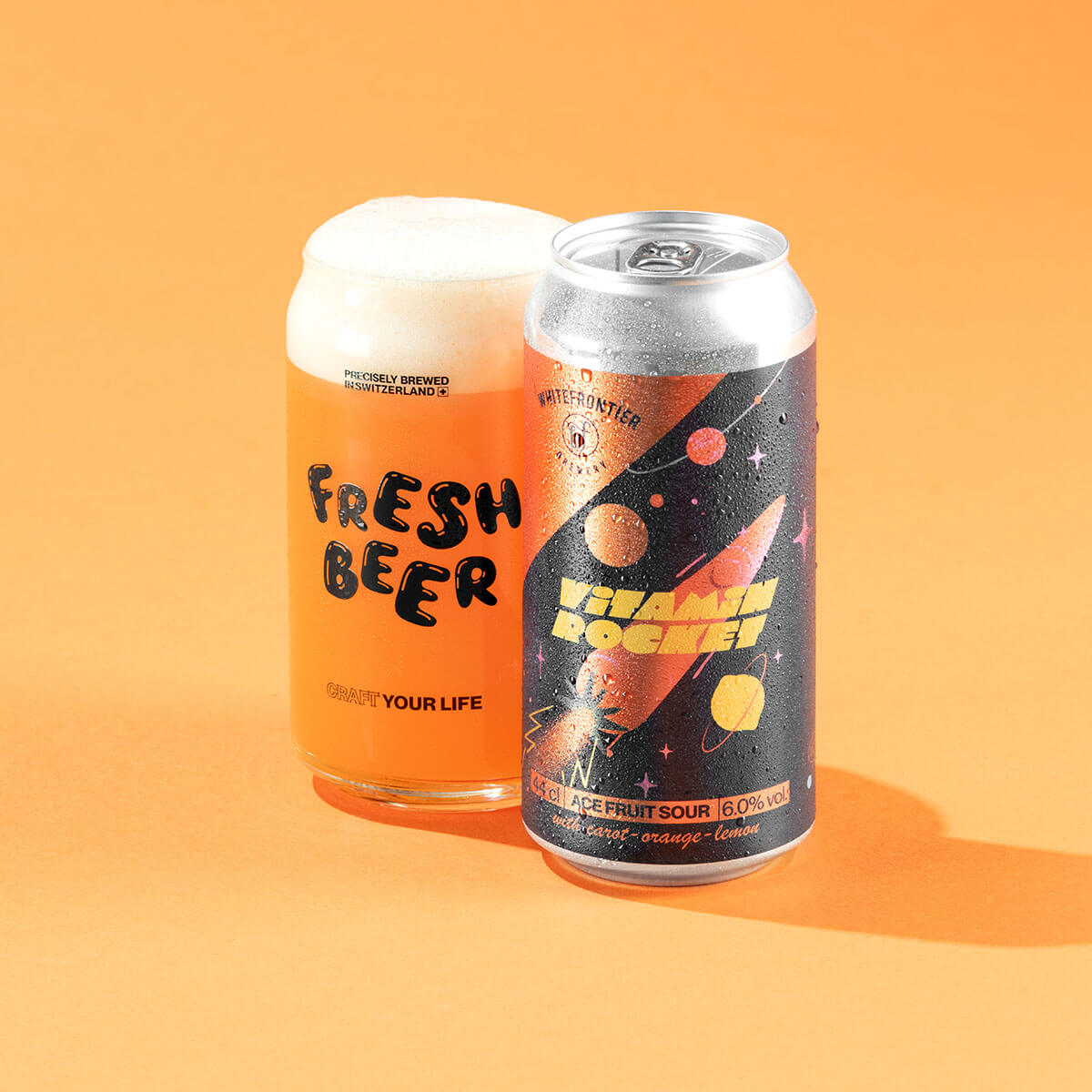 Biere bleu marine canette 44cl avec verre et biere orange sur fond orange. Carotte rocket dans lespace