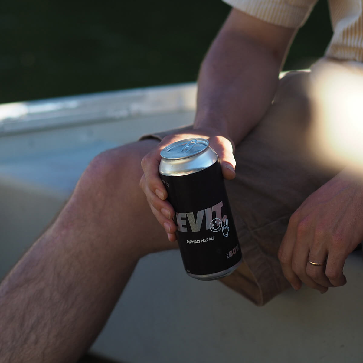 un homme tient une bouteille de bière sur une barque
